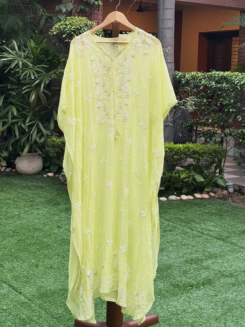 A lime green chikankari kurta set on a hanger in a garden